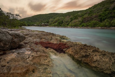 Rocky coast, long bay by the sea at sunset. Dangerous view of the Caribbean Sea. Tropical climate