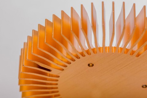 Closeup of fins and mounting surface on round copper computer heat sink on white background