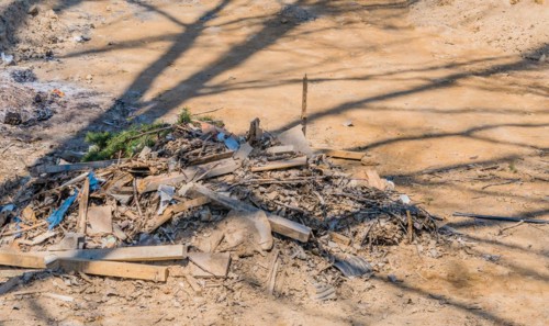 Pile of construction debris and wood scraps shadowed by a tree, in South Korea