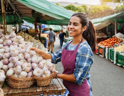 Food, spices, garlic, Allium sativum, many bulbs on a market stall, woman as saleswoman in Italy,