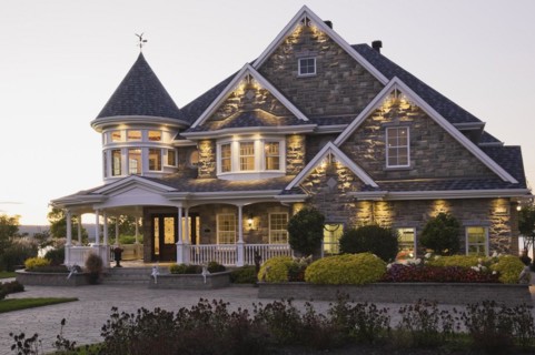 Elegant grey stone with white trim and blue asphalt shingles roof Victorian home facade at dusk in