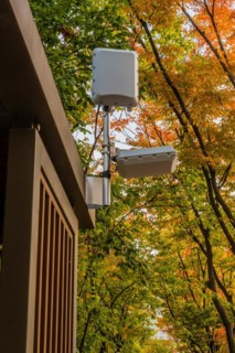 Wifi communication equipment mounted on top of wooden gazebo under trees in public park in South