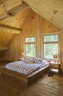 King size bed with wooden frame in master bedroom on upstairs floor inside handcrafted Eastern