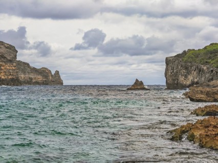 Rocky coast, long bay by the sea at sunset. Dangerous view of the Caribbean Sea. Tropical climate