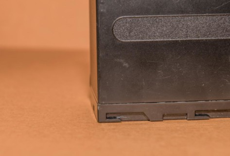 Closeup side view of used Lithium-ion battery on brown background. Selective focus on locking