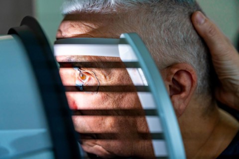Close-up photo of a senior man receiving a laser treatment for glaucoma in a clinic