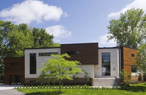 Beige stone with brown stained cedar wood modern cubist style residential home facade in spring,