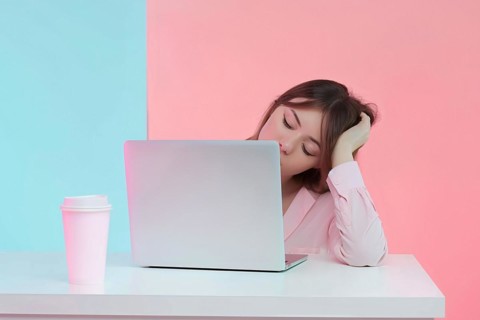 Tired woman falling asleep in front of computer at desk. Studio background. KI generiert,