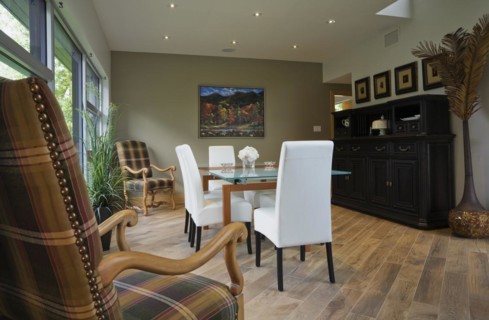 Clear glass top table and white leather high back chairs in dining room with beige ceramic tile
