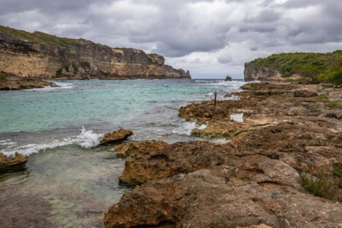 Rocky coast, long bay by the sea at sunset. Dangerous view of the Caribbean Sea. Tropical climate