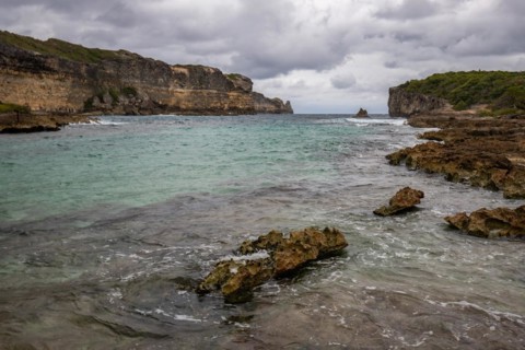 Rocky coast, long bay by the sea at sunset. Dangerous view of the Caribbean Sea. Tropical climate