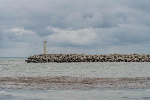 White lighthouse on a protective stone breakwater jutting out into a cloudy sea, in Ulsan, South