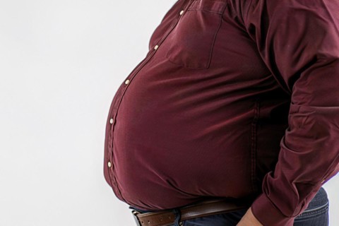 Close up of fat belly of heavily obese man in red shirt on white background. KI generiert,