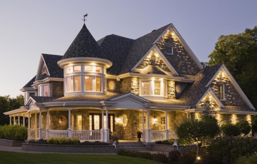 Elegant grey stone with white trim and blue asphalt shingles roof Victorian home facade at dusk in
