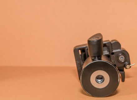 Closeup bottom view of quick release tripod head on brown background. Selective focus on thread for