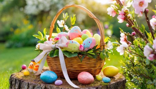 An Easter basket with colourful eggs and decorations stands in the sunny spring garden, symbol of