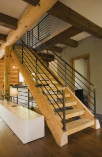 Wooden log stairs with black wrought iron railings and long cabinet table inside contemporary style