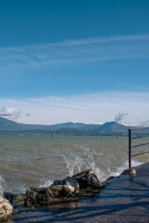 Splashing waves hitting rocks on the shore of Lake Garda, Sirmione, Lake Garda, Italy, Europe