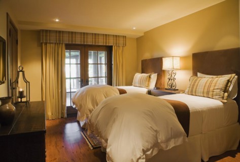 Guest bedroom with single beds and wooden dresser in basement inside luxurious log cabin home,