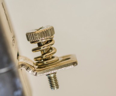 Close-up of a screw and spring mechanism, possibly from a musical instrument, in South Korea