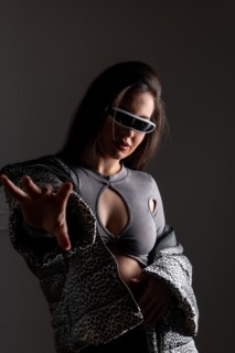 Studio portrait with grey background of a futuristic woman gesturing wearing elegant clothes and VR