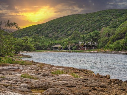 Rocky coast, long bay by the sea at sunset. Dangerous view of the Caribbean Sea. Tropical climate