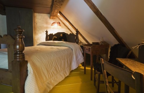 Antique wooden four-poster single bed and armoire in bedroom on upstairs floor inside old 1785