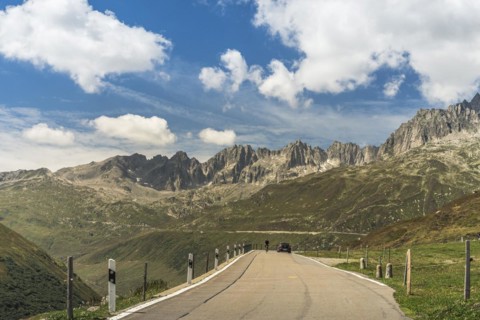 Cyclist and car driving on the Furka Pass road, mountain landscape, Realp, Canton Uri, Switzerland,