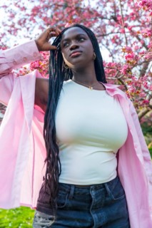 Vertical low angle view portrait of an african model posing next to flowering pink tree