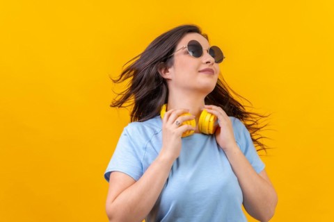 Studio portrait with yellow background of a caucasian woman moving her long hair while holding