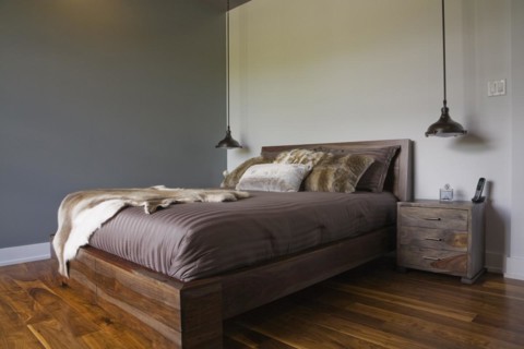 Queen size wooden base bed covered with fur pelt throw in guest bedroom inside luxurious home,