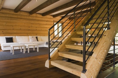 Wooden log stairs with black wrought iron railings and white cotton cloth upholstered sofas in