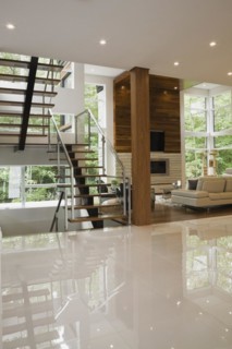 Wood, metal and glass staircase leading to living room with creamy beige L-shaped leather sofa