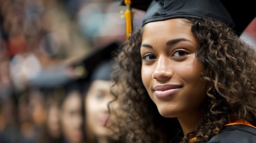 Smiling pretty female student in cap and gown at a graduation ceremony, representing educational