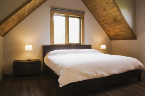 King size bed in master bedroom on upstairs floor inside contemporary style log home, Quebec,