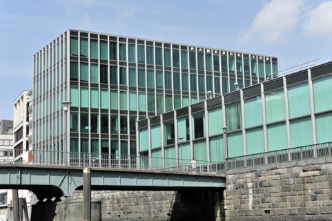 Hamburg Sued Reederei, A building with a green glass facade stands next to a bridge in an urban