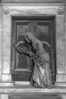 Sculpture of an old woman at a door with an hourglass, Monumental Cemetery, Cimitero monumentale di