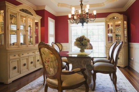 Glass top table with high-back wooden and upholstered chairs in dining room with buffets inside