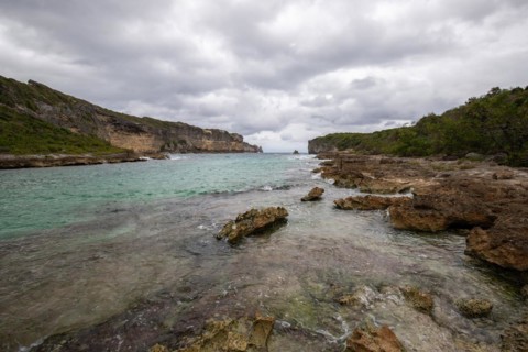 Rocky coast, long bay by the sea at sunset. Dangerous view of the Caribbean Sea. Tropical climate