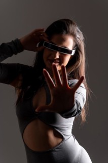 Studio portrait with grey background of a futuristic woman playing and gesturing using virtual