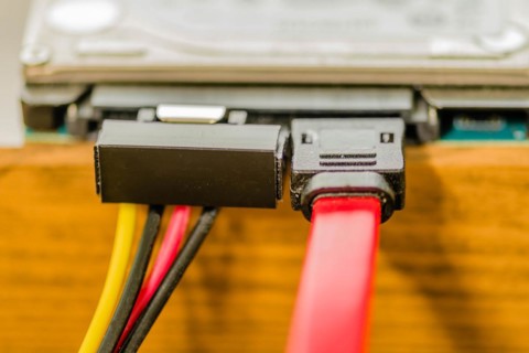 Closeup of sata cable plugged into computer hard disk on work bench. Left cable transfers power,