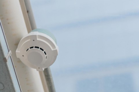 Electronic smoke detector on ceiling of enclosed pedestrian walkway with blurred plexiglass in