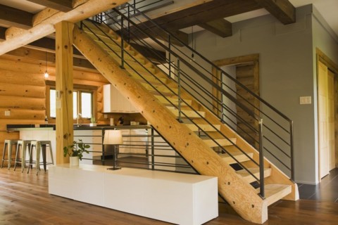 Kitchen with white wooden cabinets, metal bar stools and wooden log stairs with black wrought iron