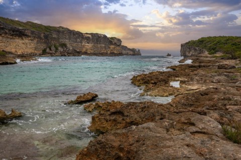 Rocky coast, long bay by the sea at sunset. Dangerous view of the Caribbean Sea. Tropical climate