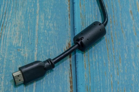 Black HDMI monitor cable isolated on blue wood grain background