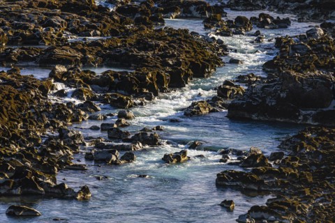 Rushing stream meanders through rocks to the Pjofafoss waterfall, Sudurland, Iceland, Europe