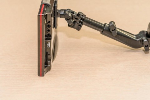 Side view of automobile navigation system with attached mounting arm showing the various IO ports