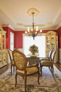 Glass top table with high-back wooden and upholstered chairs in dining room with buffets inside