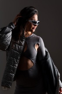 Vertical studio portrait with grey background of a futuristic woman in fashion clothes wearing
