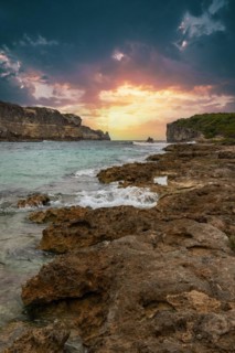Rocky coast, long bay by the sea at sunset. Dangerous view of the Caribbean Sea. Tropical climate